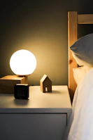 A cozy bedroom scene featuring a bedside table with a glowing fragrance lamp and a stack of books.