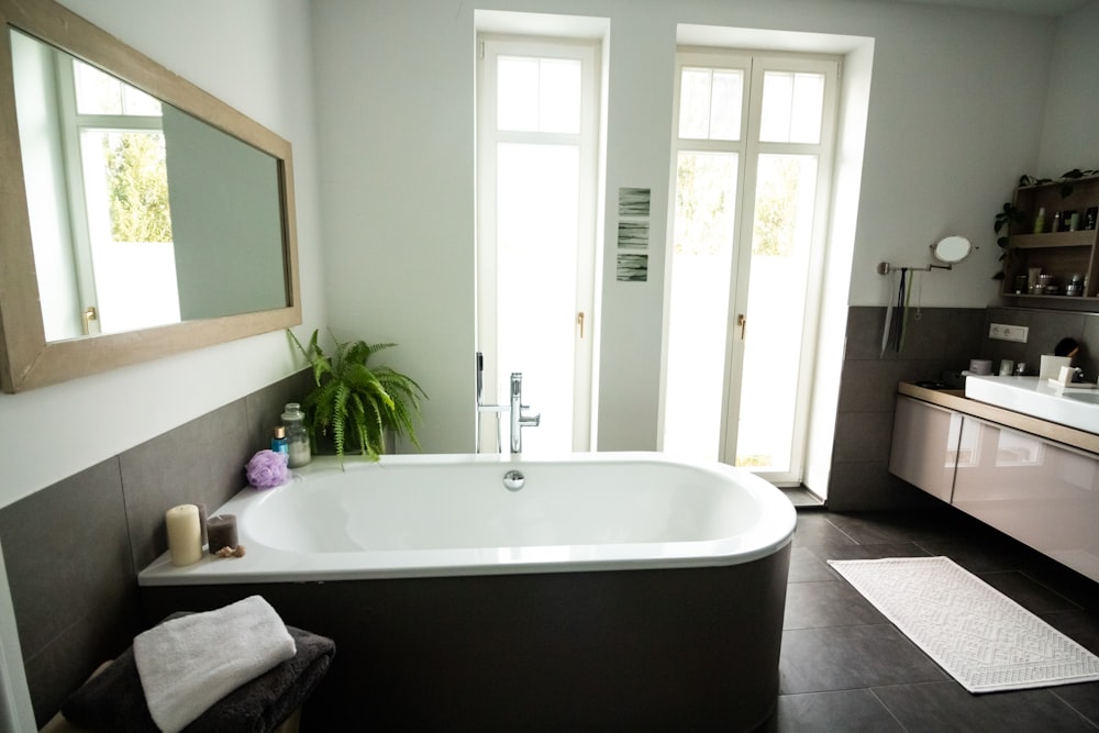 white ceramic bathtub near white wooden framed glass window