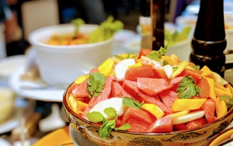Bright summer fruit bowl with berries, melon, and mint leaves glistening in natural light.