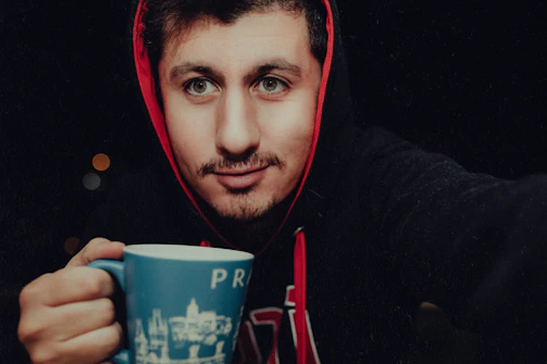A happy customer wearing a Printnest t-shirt outdoors, smiling and holding a matching mug.