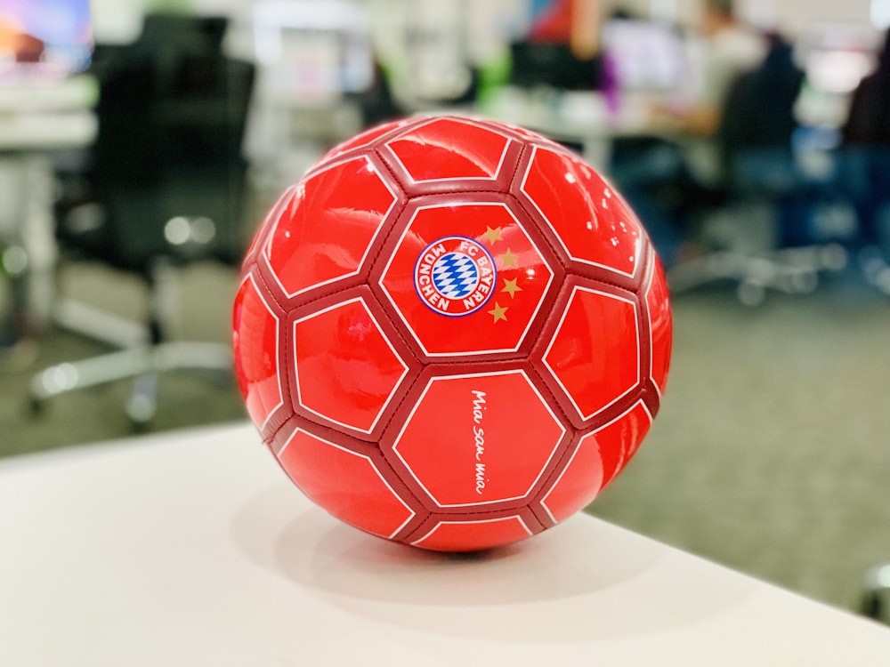 Balón de fútbol rojo sobre mesa blanca