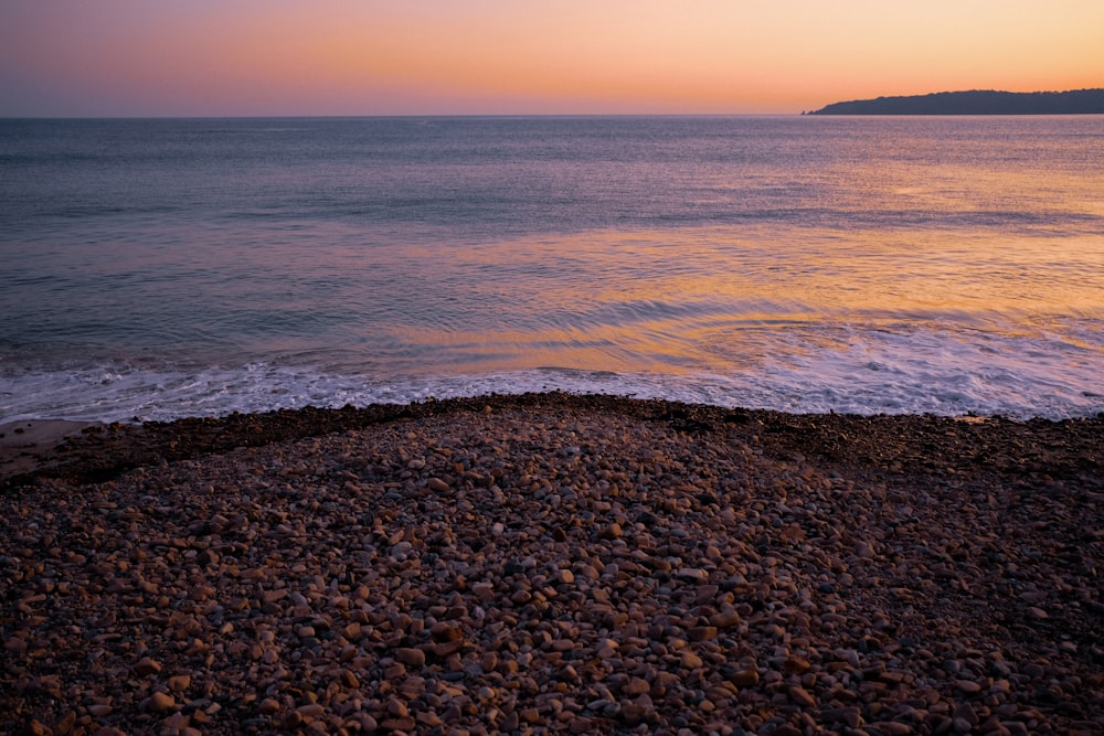 sea waves crashing on shore during sunset