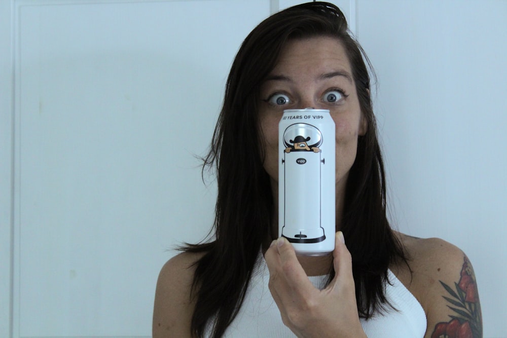 woman in white tank top holding white samsung smartphone