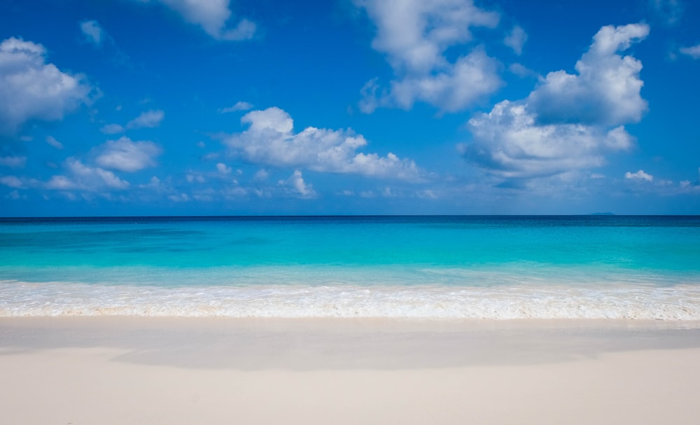 mar azul bajo el cielo azul y nubes blancas durante el día