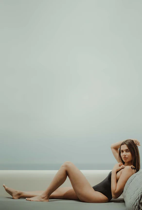 Close-up of a black elegant one-piece swimsuit with subtle cutouts, displayed on a resort chair.