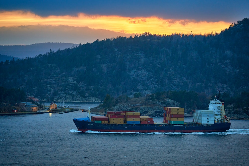 red and white cargo ship on sea during sunset