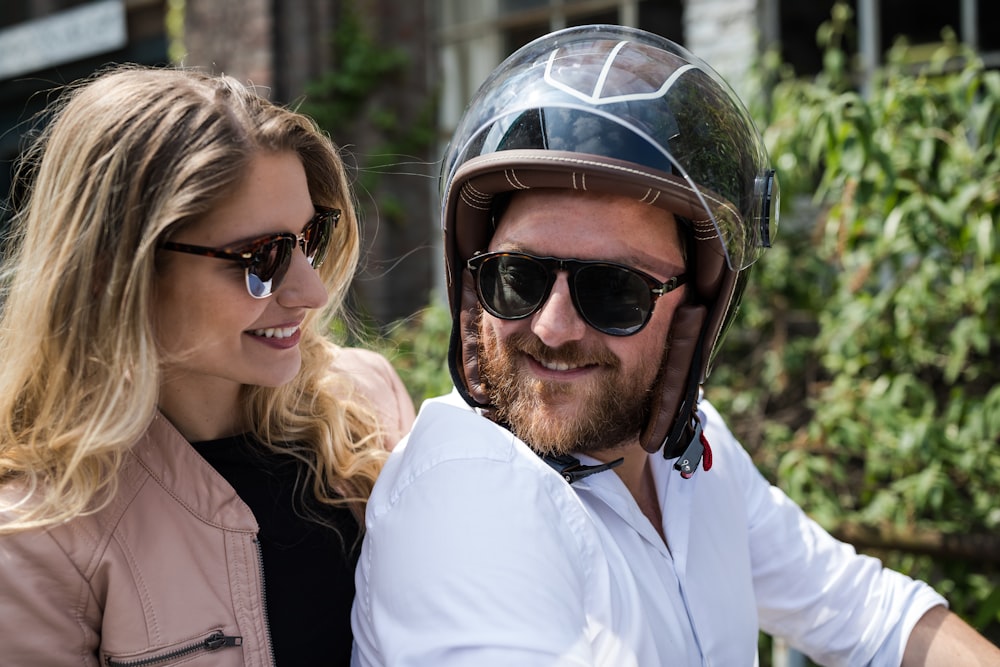 man in white shirt wearing black sunglasses beside woman in black jacket