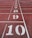 A running track with white lane markings and large numbers from 1 to 10 painted sequentially. The track surface is a reddish-brown color, typical of many athletic tracks.