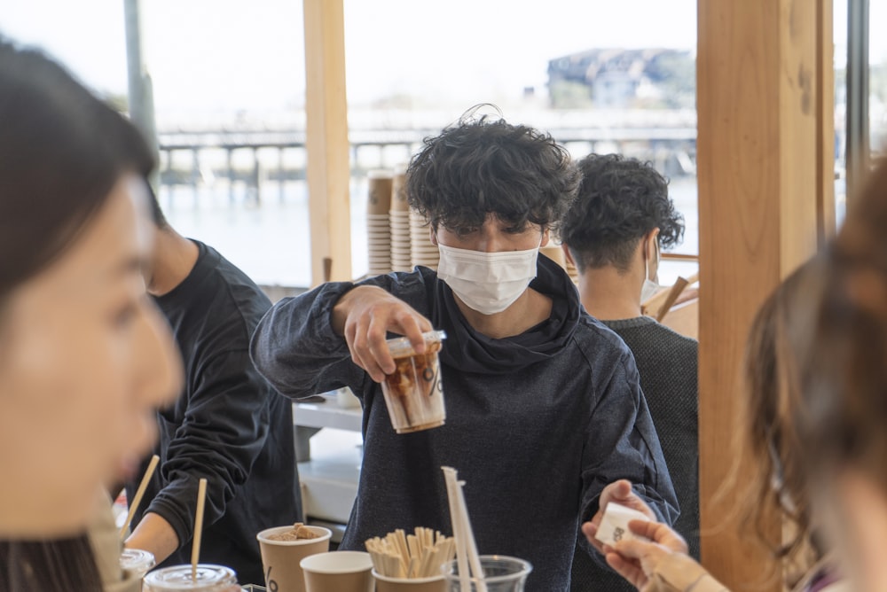 man in black crew neck t-shirt holding clear drinking glass