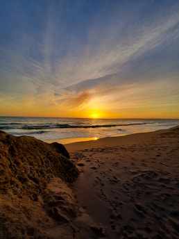 sea waves crashing on shore during sunset
