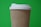 A disposable coffee cup with a textured brown sleeve and white plastic lid is set against a vibrant green background.