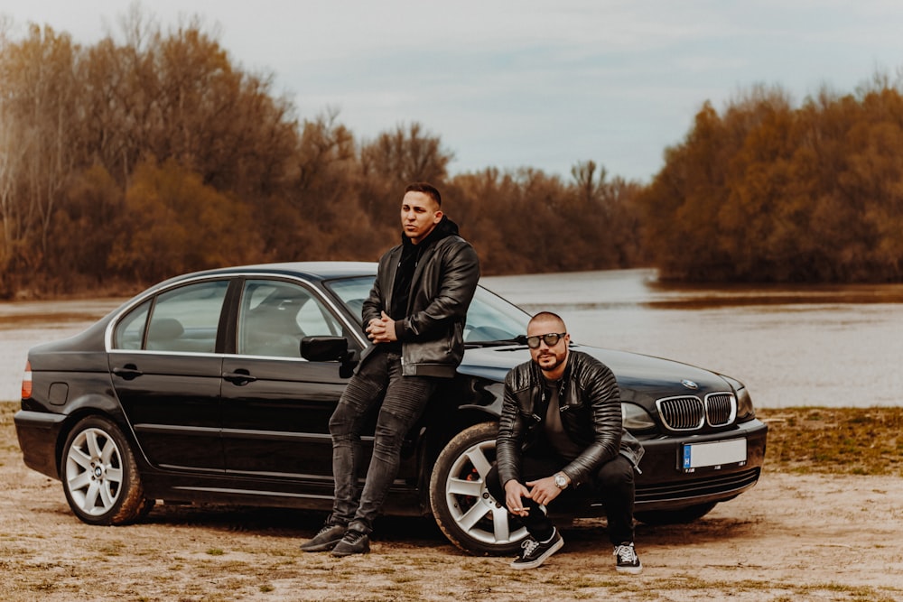 man in black jacket and black pants sitting on black car