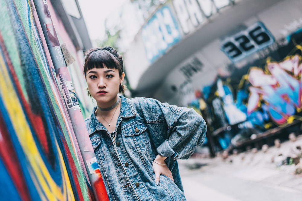 woman in blue denim jacket standing near wall