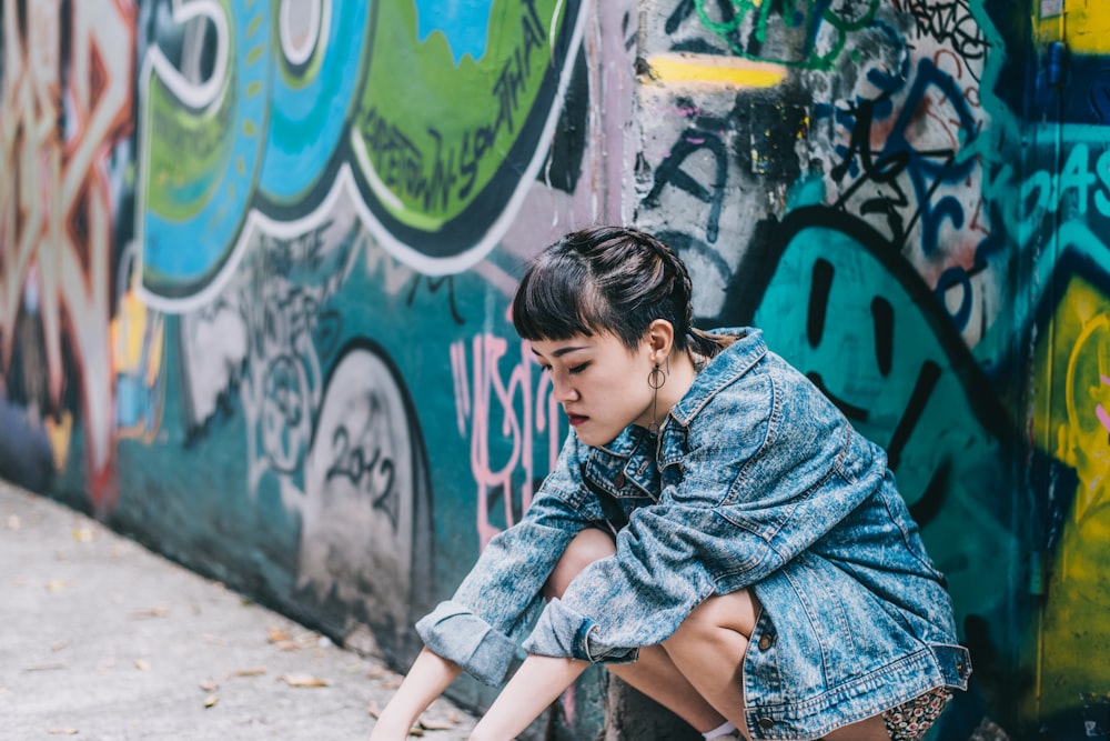 girl in blue denim jacket sitting on concrete bench