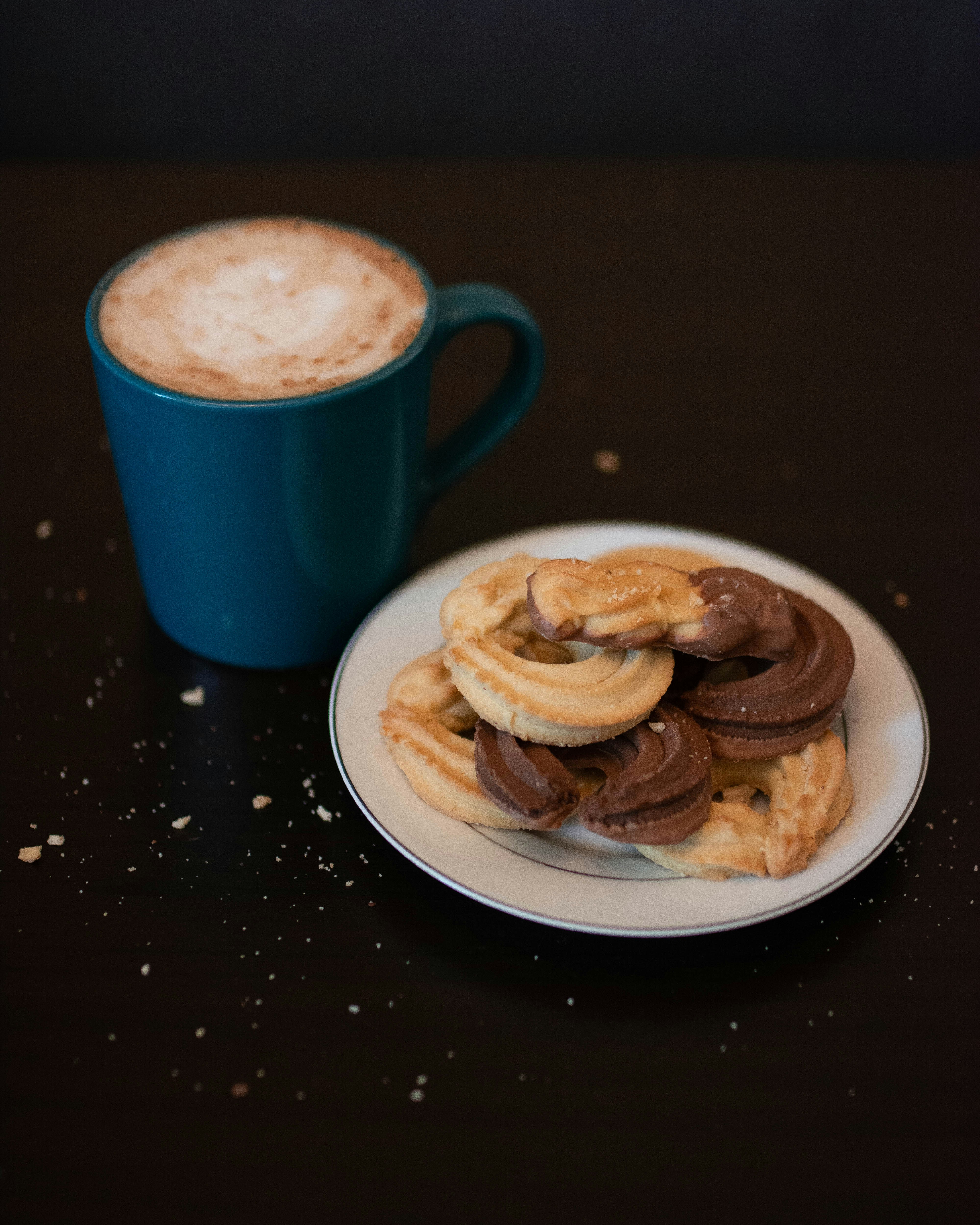 two brown breads on white ceramic plate beside red ceramic mug