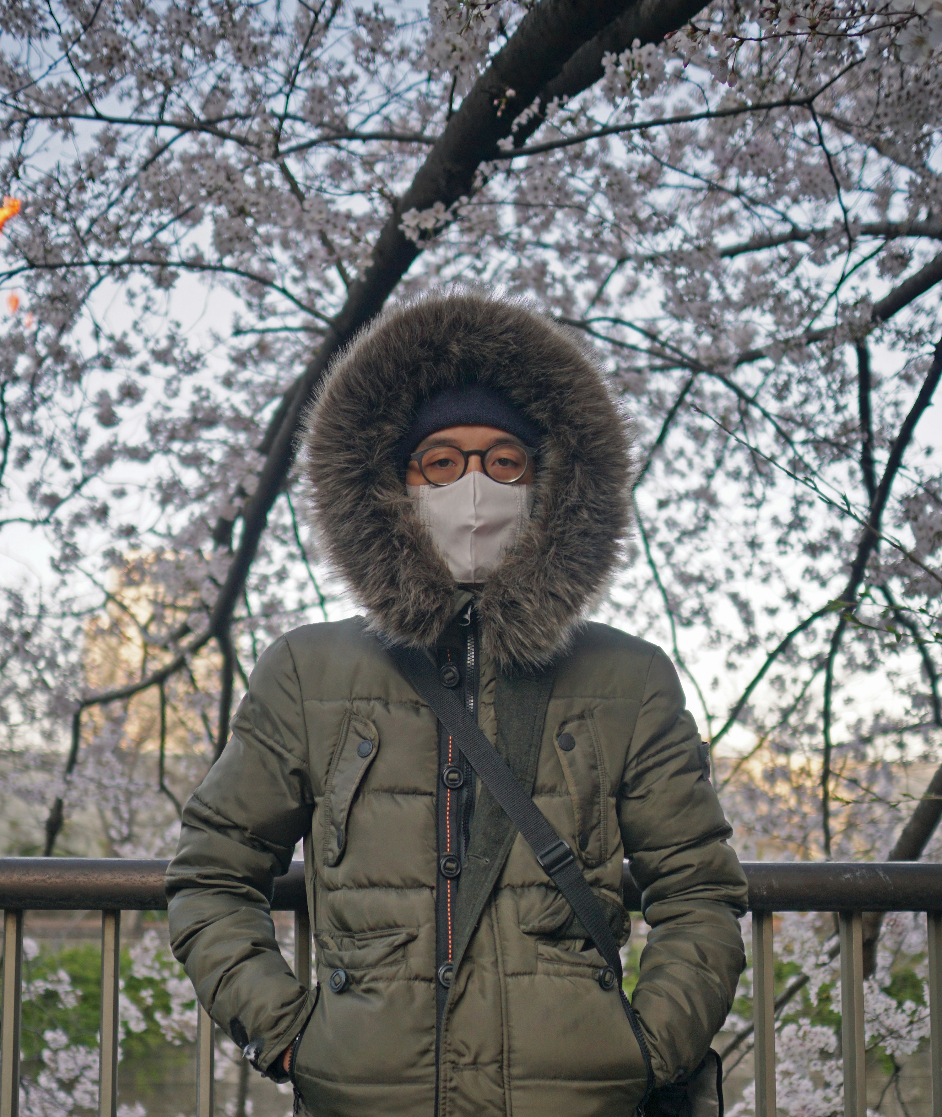 person in brown parka jacket standing near brown wooden fence during daytime