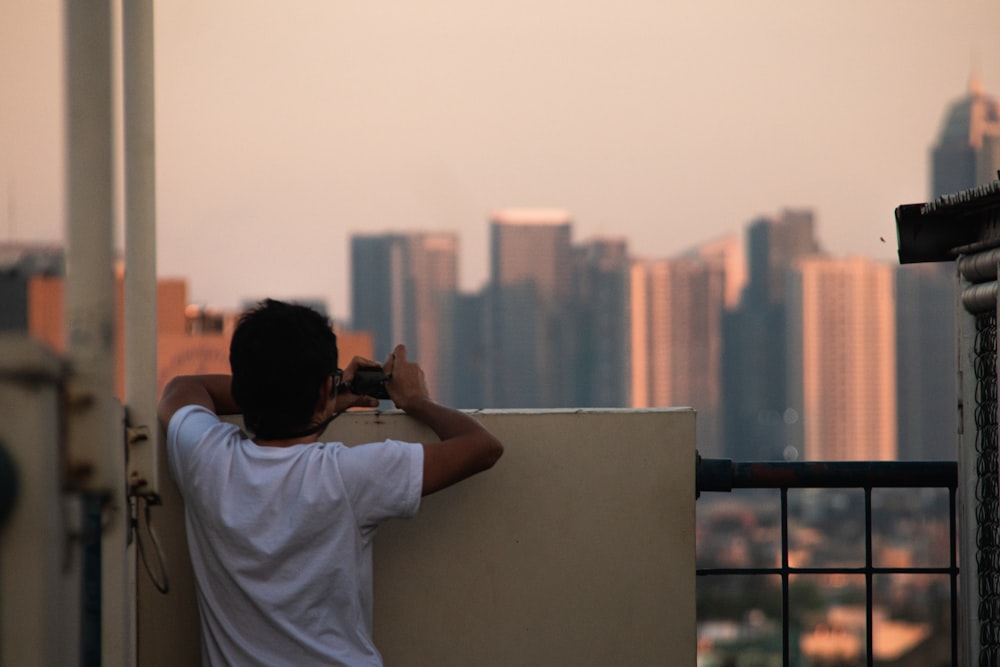 man in white t-shirt holding black smartphone