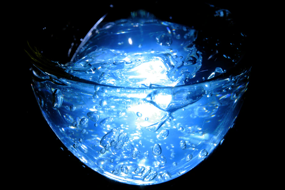 Close-up of a scientist holding a vial with a glowing blue liquid in a modern lab