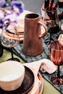 brown ceramic pitcher beside white ceramic mug on table