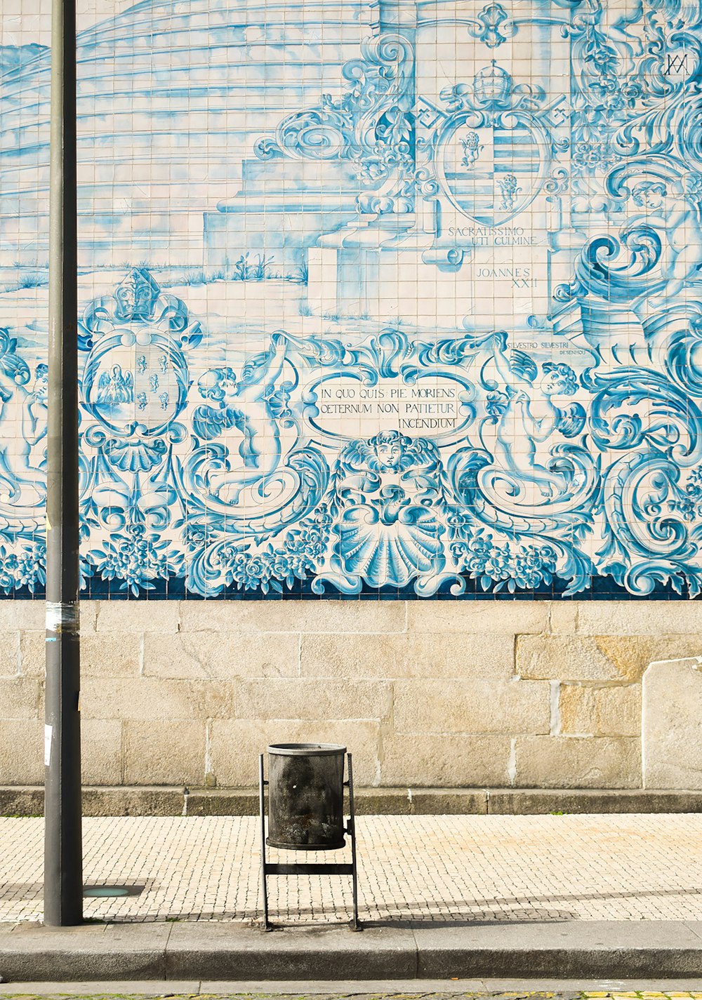 black trash bin beside white wall