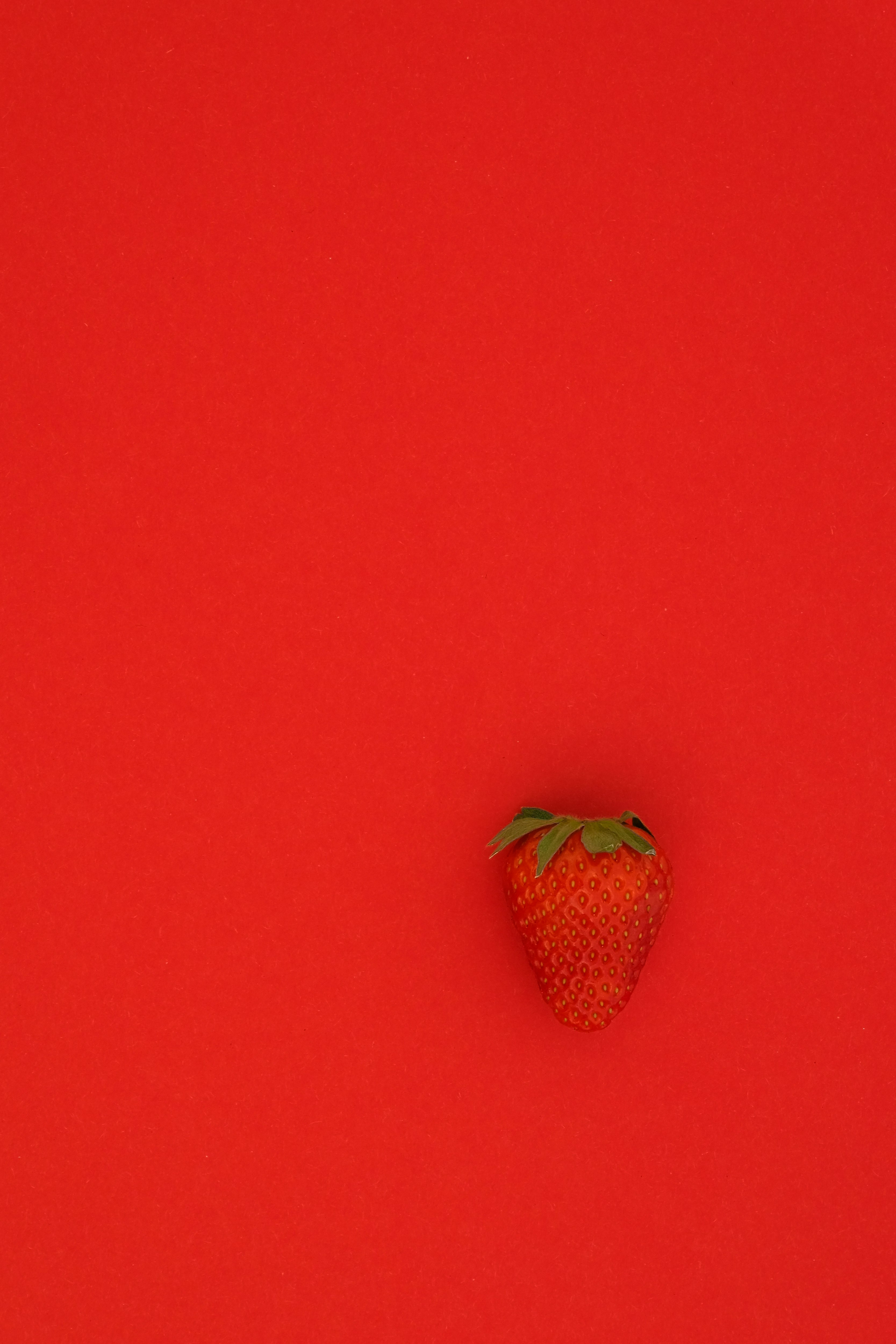 red strawberry fruit on red surface