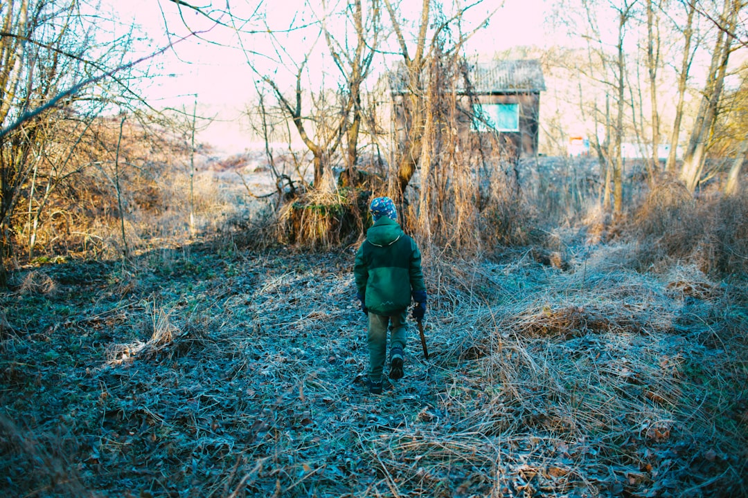 man in green jacket walking on brown dried grass during daytime