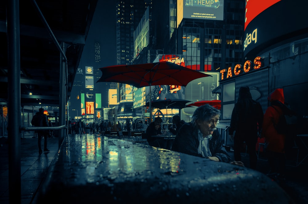 people sitting on chair under red umbrella during night time