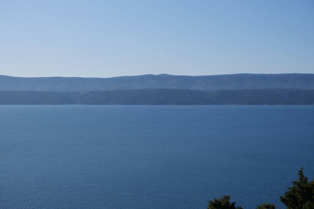 green mountain beside blue sea under blue sky during daytime