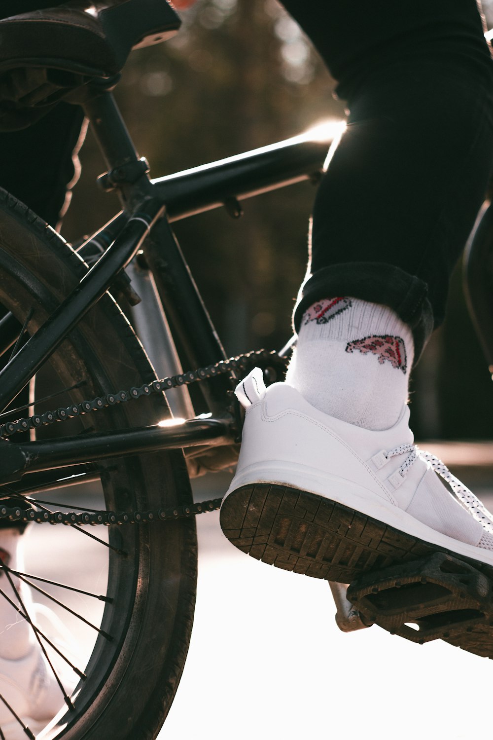 person wearing white nike athletic shoes riding bicycle