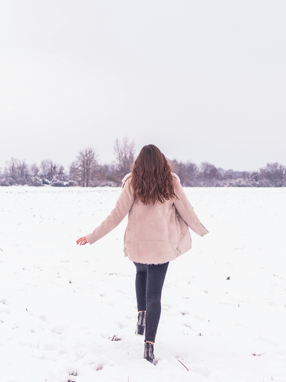 woman in white long sleeve shirt and black pants standing on snow covered ground during daytime