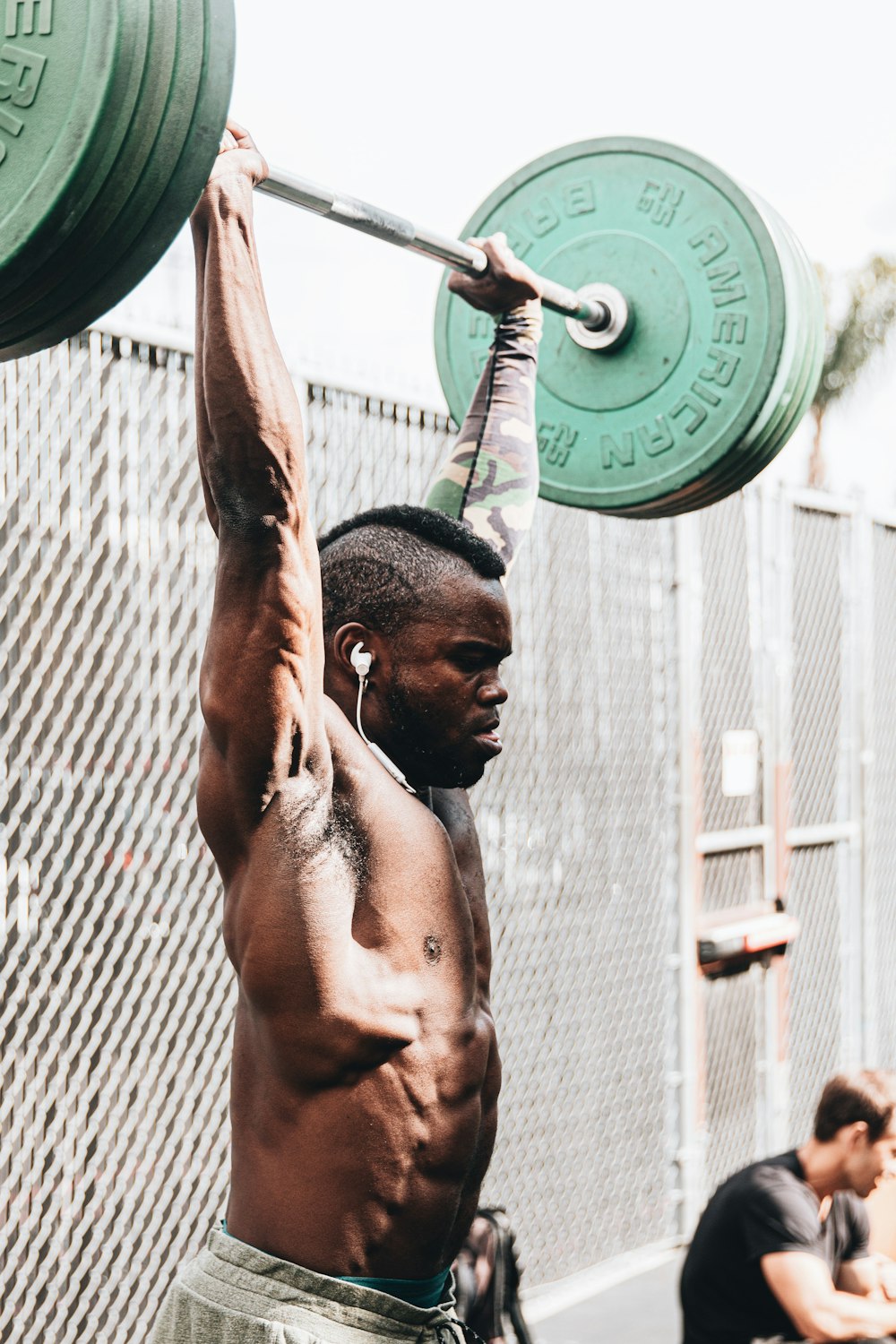 topless man holding green dumbbell