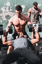 A trainer helping a focused man with posture during a workout.