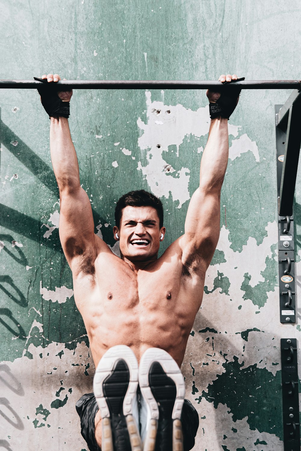 topless man in white shorts holding black metal bar