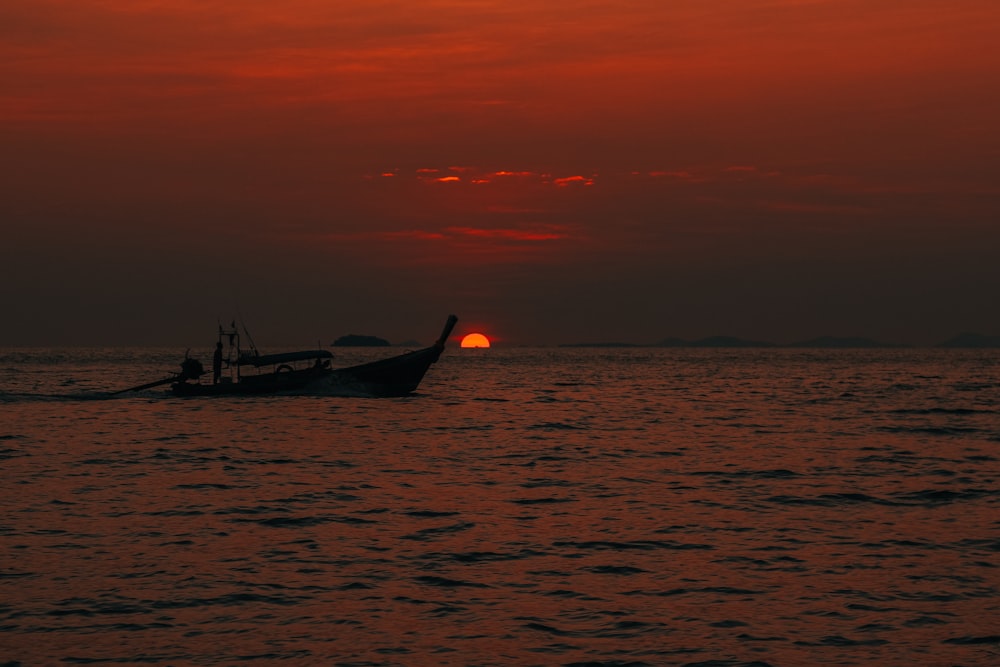 silhouette of person riding on boat during sunset