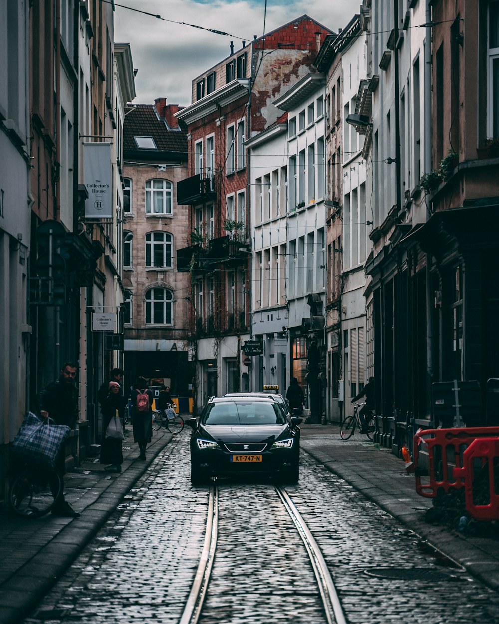 cars parked on side of the road in between buildings during daytime