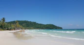 Happy travelers enjoying a sunny beach vacation with clear blue skies.