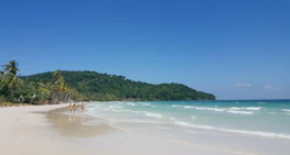 Happy travelers enjoying a sunny beach vacation with clear blue skies.
