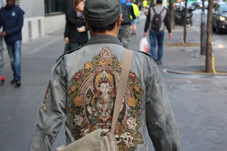 Close-up of a customer wearing a Vixtta jacket with mythological embroidery on a city street