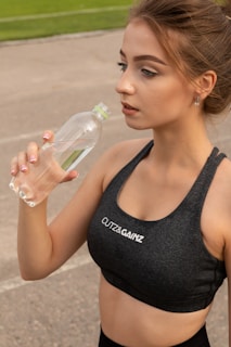 woman in black tank top holding clear plastic bottle