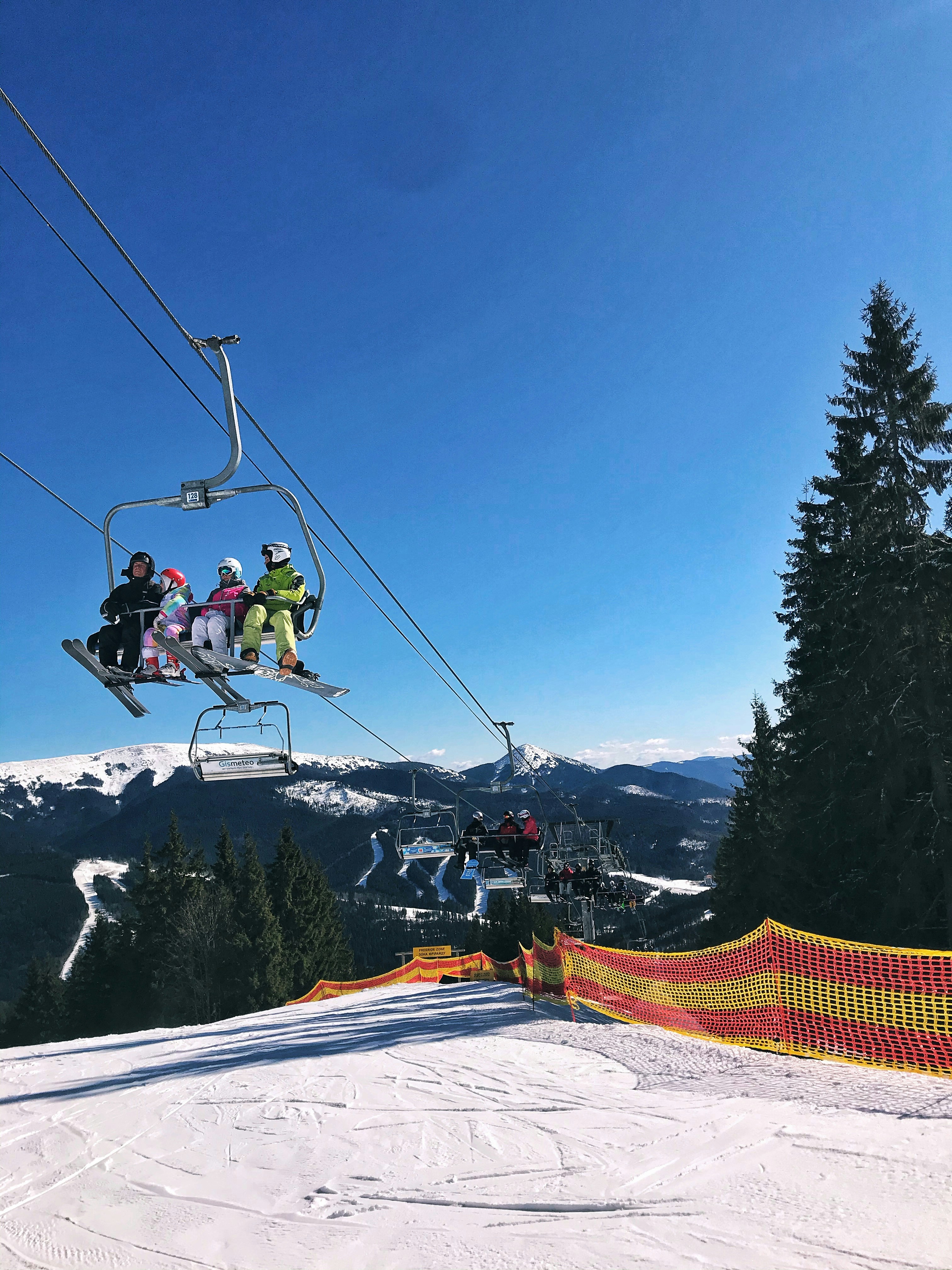 people riding ski lift over snow covered mountain during daytime