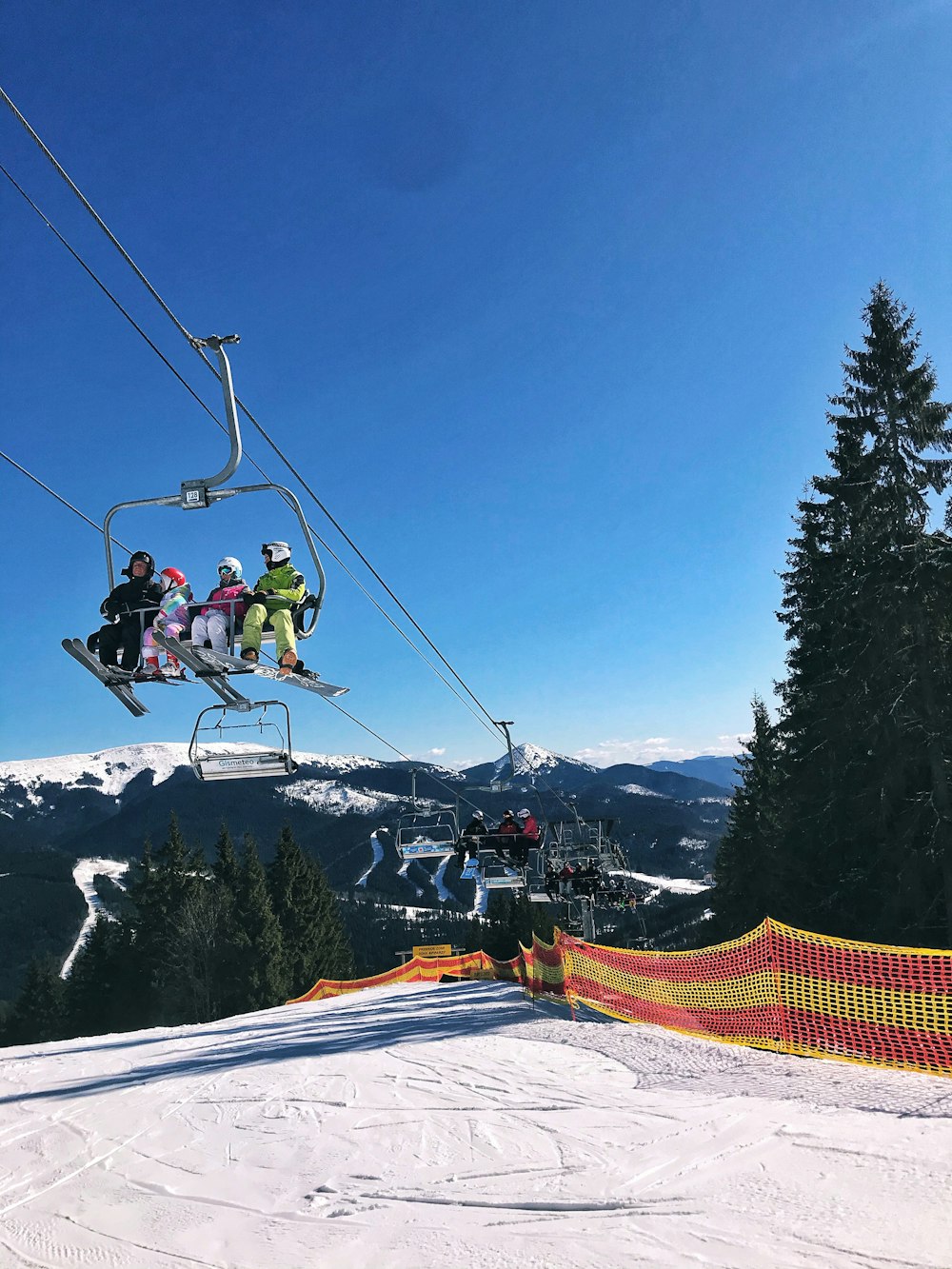 Personen, die tagsüber mit dem Skilift über den schneebedeckten Berg fahren