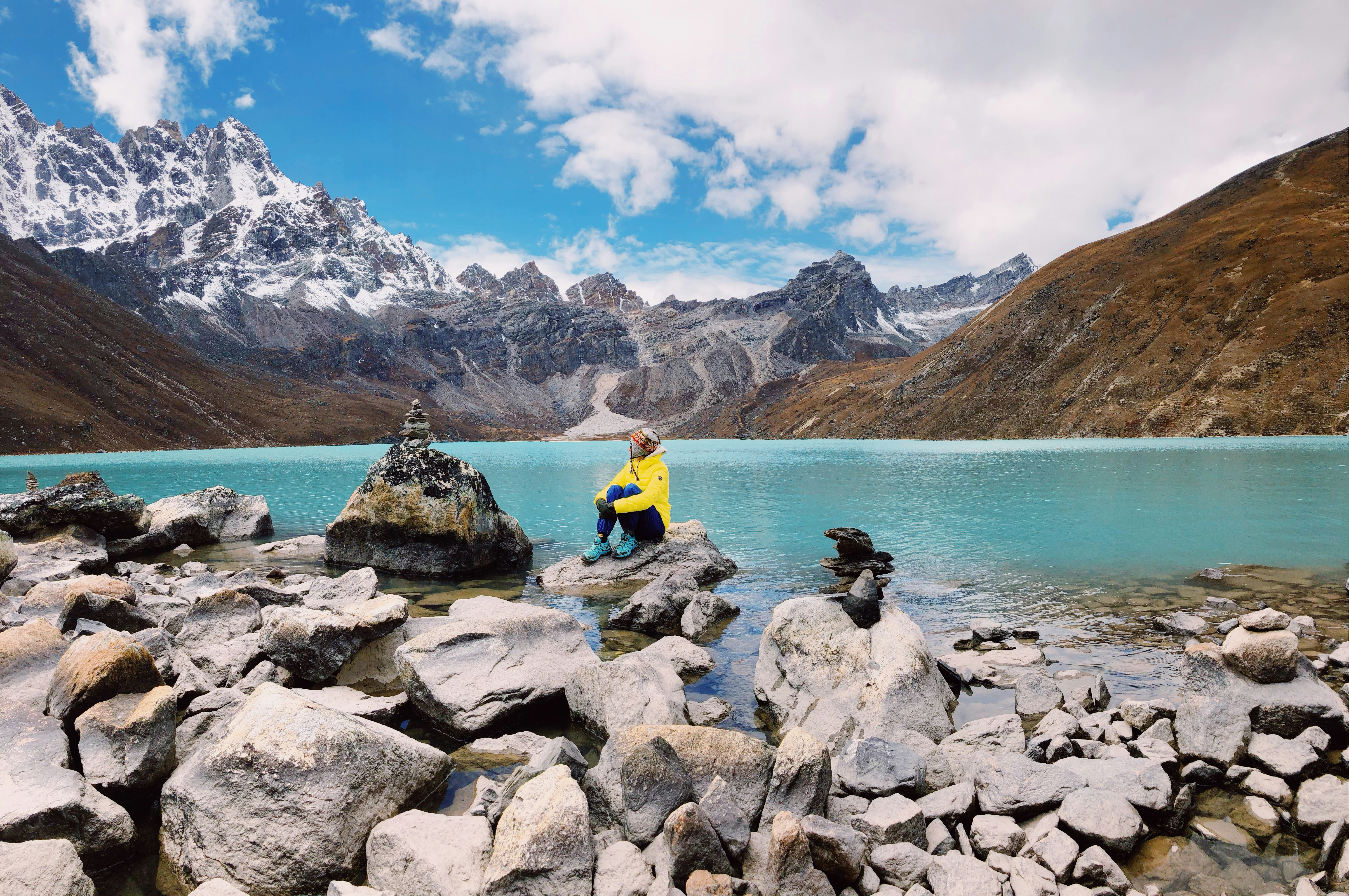 Trekker resting beside a turquoise glacial lake in the Gokyo Valley