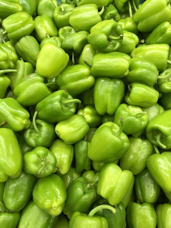 Bright green bell peppers neatly stacked, showcasing their glossy skin and freshness.