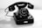 A vintage rotary dial telephone is placed on a wooden surface. The phone is black with a circular dial featuring numbers and letters. Its handset rests on top of the main body, connected by a coiled cord.