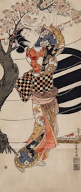 A traditional Japanese woodblock print depicting a woman in an ornate kimono adorned with intricate patterns and colorful designs. She is reaching up towards a cherry blossom tree, with pink blossoms and some hanging elements. The artwork exhibits classic Japanese aesthetics and attention to detail with dynamic composition.