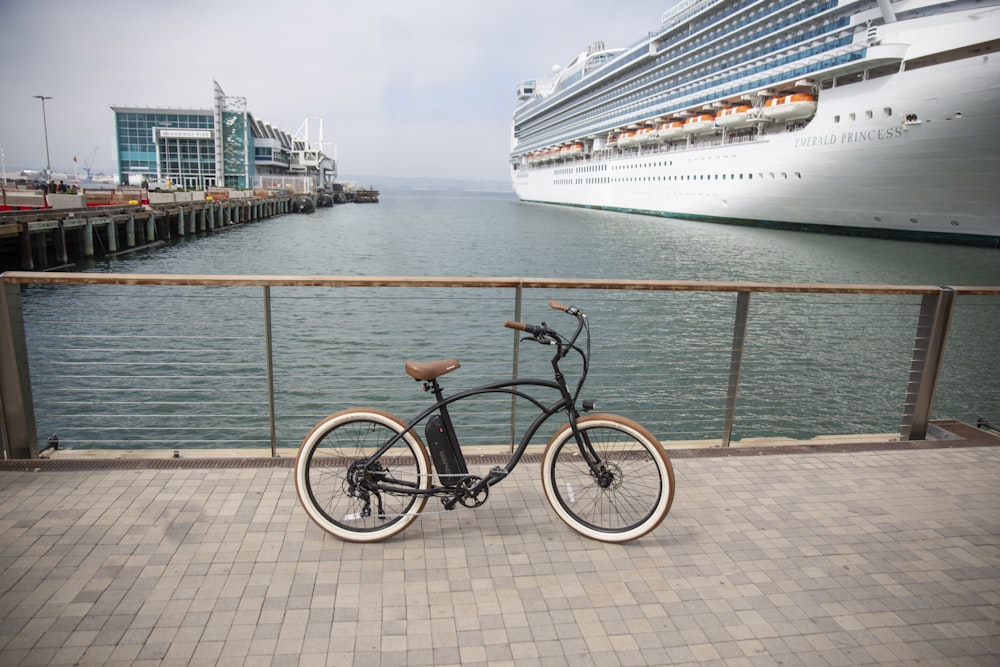 black city bike parked beside blue and white cruise ship on sea during daytime