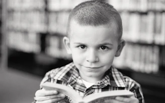 Close-up candid moment of a child flipping pages with a joyful smile in charcoal-toned lighting.