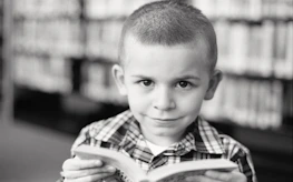 Close-up of a child holding a book with a hopeful expression, symbolizing opportunity.