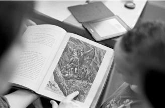 grayscale photo of person holding book