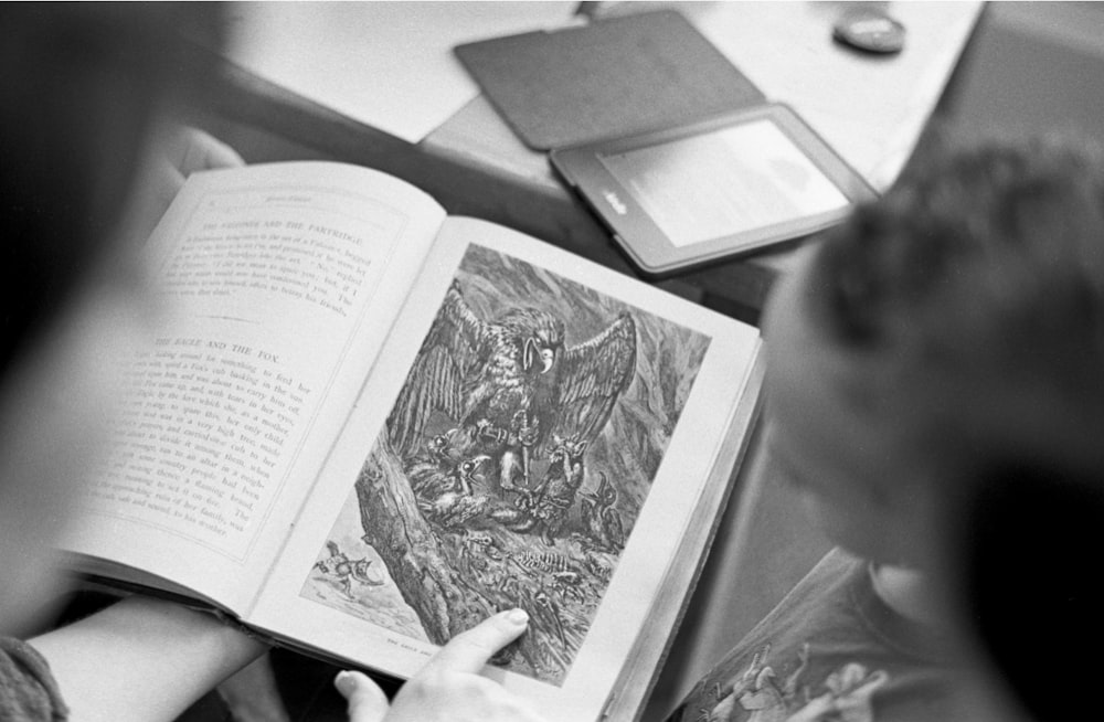 Foto en escala de grises de una persona sosteniendo un libro